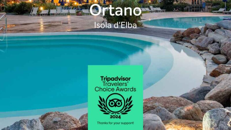 Basen otoczony skałami i roślinami, z obiektem hotelowym i wyróżnieniami Tripadvisor na pierwszym planie. Wyspa Elba.