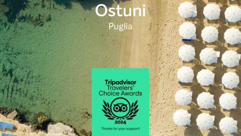 Widok z lotu ptaka na Ostuni, Apulia, z plażą, parasolami i logo nagród Tripadvisor 2024.