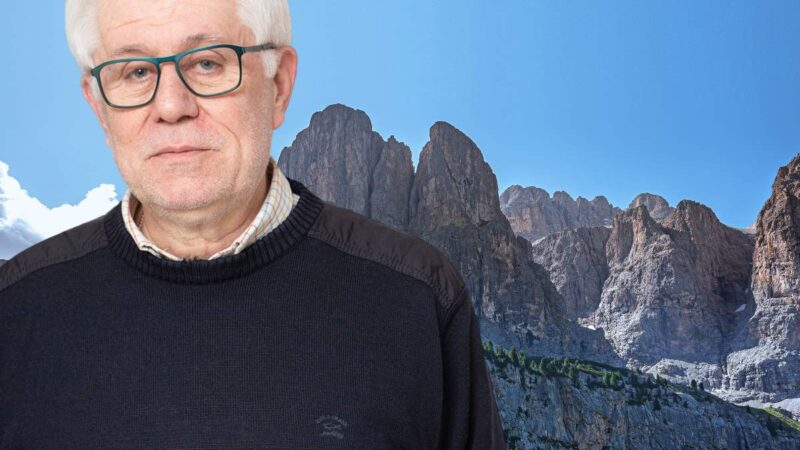 Elderly man with glasses in front of a mountain background, text with the name Graziano Debellini and role President.