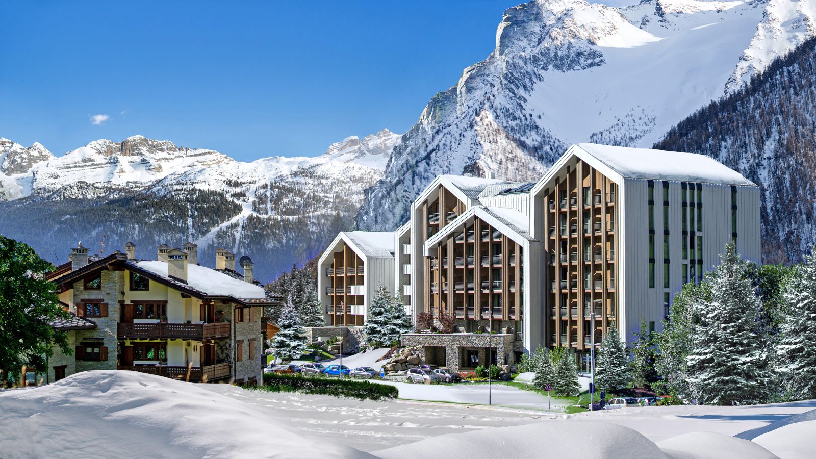 Modern building in alpine style with snow-capped mountains in the background and trees covered in snow.