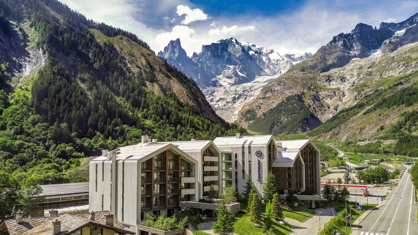 Modern hotel complex among the green and snow-capped mountains of the Alps.
