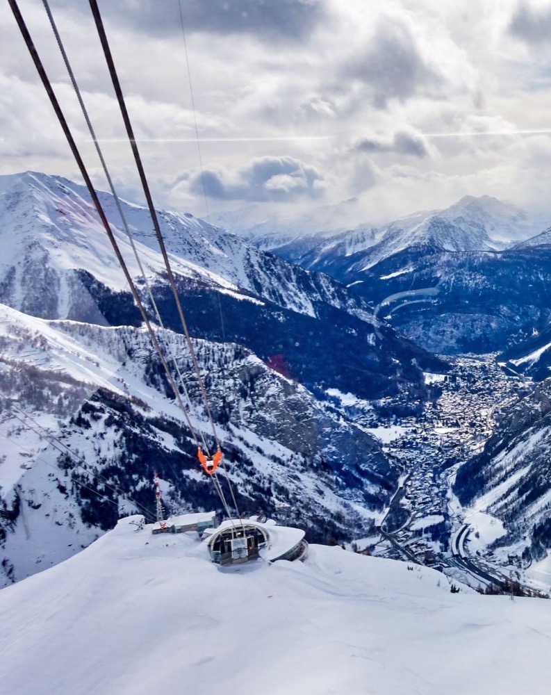 Vista di montagne innevate viste dall'elicottero in volo sopra una valle alpina.