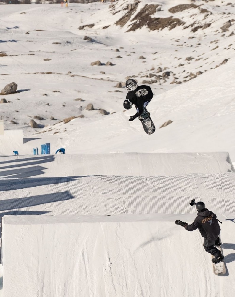 Due ragazze snowboarder sulla neve, una in aria mentre esegue un salto.
