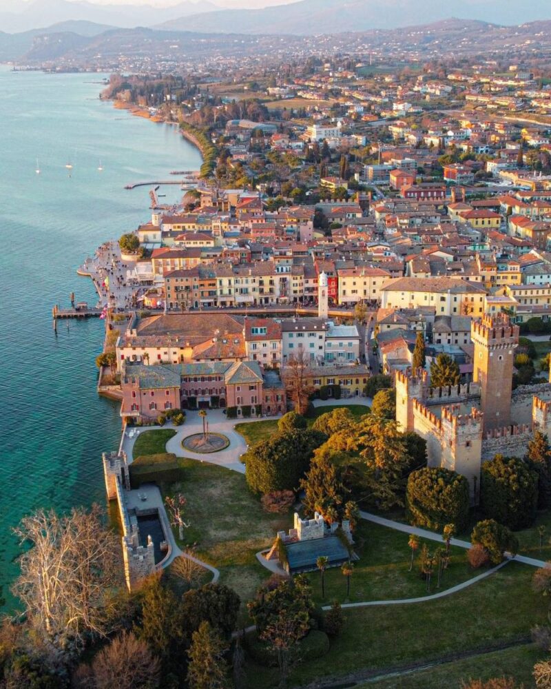 Veduta aerea del borgo di Sirmione con il castello scaligero e il Lago di Garda al tramonto.