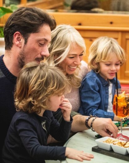 Smiling family sitting at the table with snacks and drinks, sharing a moment of togetherness.