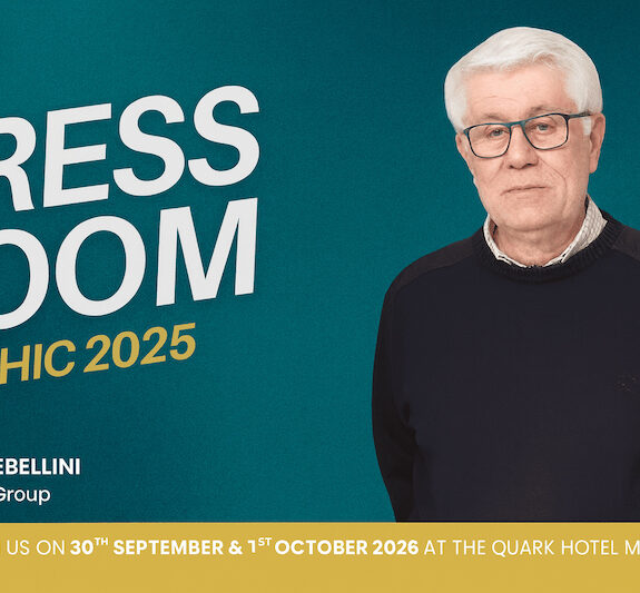 Elderly man in a dark sweater with glasses, holder of "Press Room" for ITHIC 2025 at the Quark Hotel in Milan.