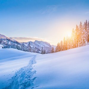 Panoramic view of beautiful winter wonderland mountain scenery with traditional mountain cabin the background in the Alps in golden evening light at sunset.